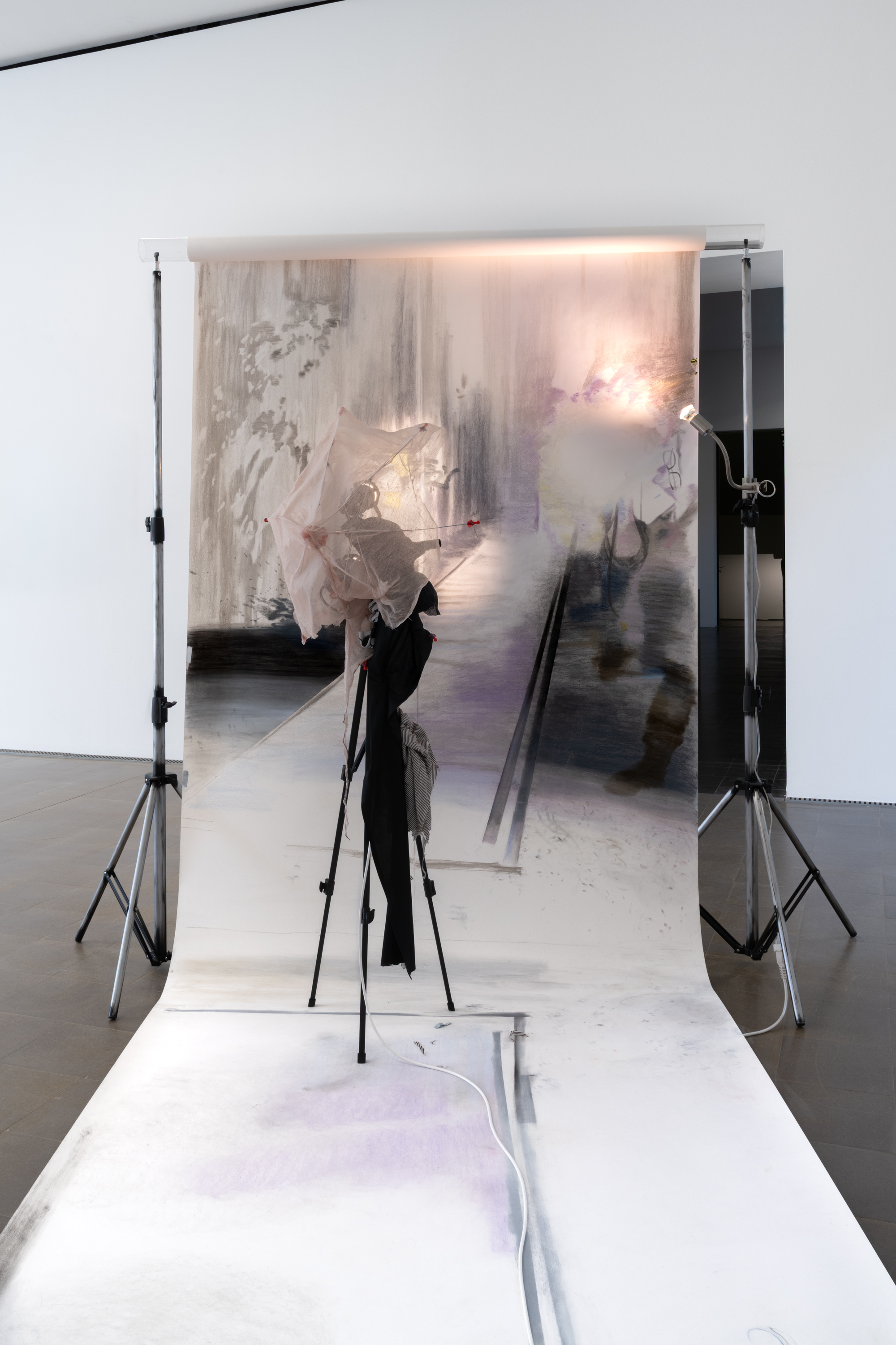 Estéfana Román Matesanz, *A Flick to Stop the Ball in Mid-Flight*, 2025/26. Tripod, umbrella, clothing, wax
and fabric, pastels, charcoal and pencil, spray paint on paper, Dimensions variable. Photo: Finn Curry.